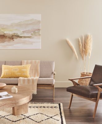 A living room with wood floors and neutral walls painted Shiitake SW 9173 filled with midcentury modern furniture in neutral tones.