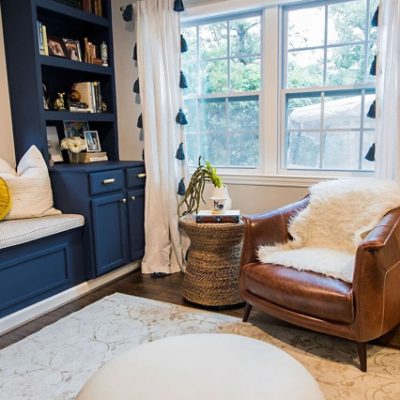 A modern designed living room with a navy blue bookshelf. SW color featured: SW 9177 Salty Dog.