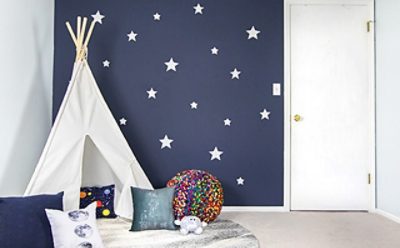 A bedroom with a white tent and blue navy walls with stars.
