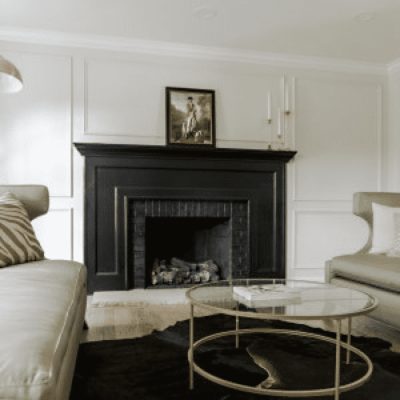 A white walled living room with a dark floor and dark fireplace., by brickhousedesigns.