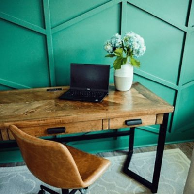 A home office with a wooden desk in front of a wall painted in kale green sw 6460 by @carolinareclaimed.