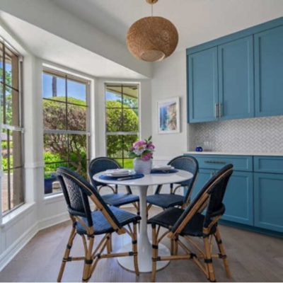 A kitchen nook with bright blue cabinets with a round table by @contigoflowertherapy.