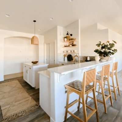 A kitchen with a a bar top and wooden bar chairs with walls painted in origami white sw 7636 by @fabulousatanystage.