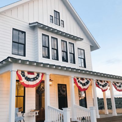 A modern countryside home with a wrap around porch with columns painted in pure white sw 7005 by @gallagherboyfarm.