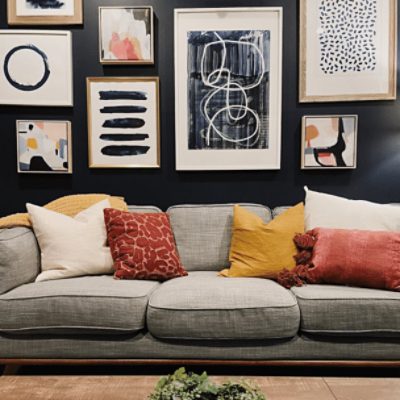A living room with a large couch and many pictures on a wall painted in naval sw 6244 by @halliebeattie.