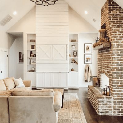 A high slanted ceiling family room with a large brick fireplace with walls painted in natural choice sw 7011 by @jacobsfarmstead.