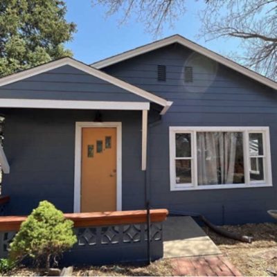 The front of a home painted a dark gray blue by @kindhomesolutions.