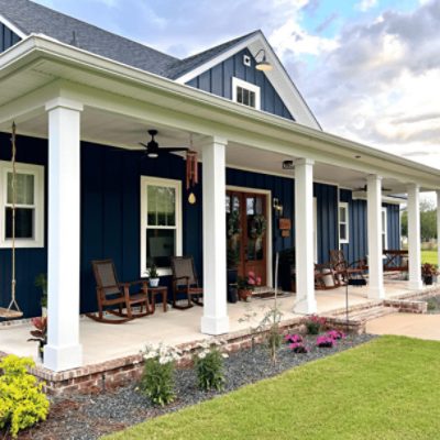 A beautiful modern home with white columns, front porch, lush grass and exterior painted in naval sw 6244 by @oldplankfarmhouse.