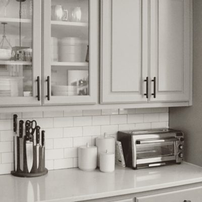 A kitchen with white tile backsplash, counters and white cabinets with walls painted in lazy gray sw 6254 by @stayhomestyle_.