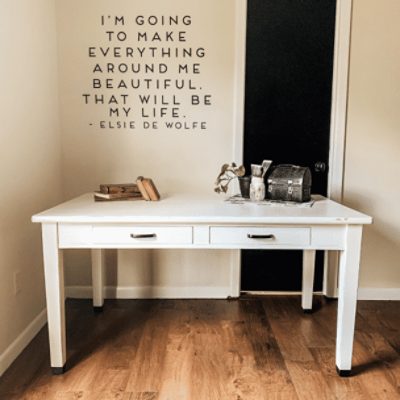 A bedroom with a white table in front of a wall with a quote painted in shoji white sw 7042 by @kendramckinneydesigns.