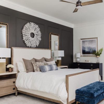 A large bedroom with a large white bed next to twin nightstands in front of a batten board wall painted in SW 7048 Urbane Bronze.