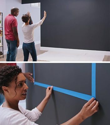A couple is using painter's tape to mask the wall before painting