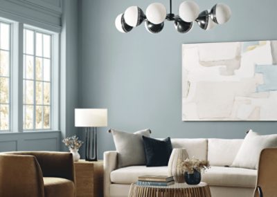 Living room painted in light blue SW paint with a cream colored couch and light brown chair with matching accents.