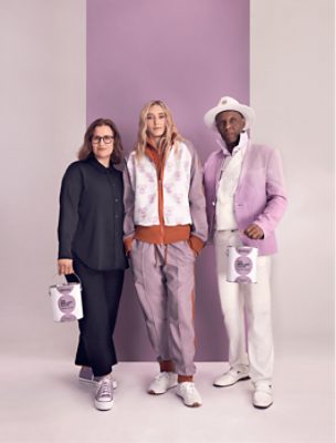 Sue Wadden, Paige Bueckers and Dapper Dan posing in front of a Radiant Lilac wall while holding The Loneliest Color branded paint cans.