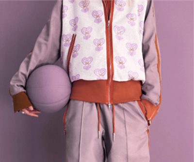 Paige Bueckers in a Loneliest Color branded track suit while holding a Radiant Lilac colored basketball.