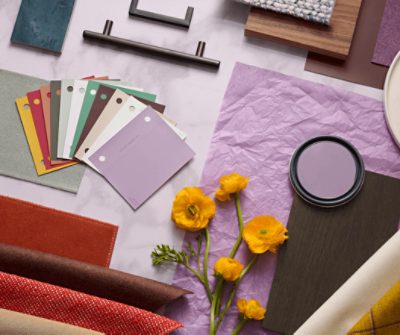A flat lay image of various textiles, color chips, hardware and flowers.