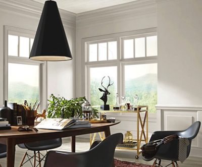 Office with cream colored walls and three windows, black chairs, a desk, and gold accents.