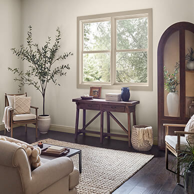 Neutral living room with chairs, plants, windows, side table with decor.