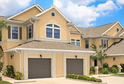 A traditional-style home with light gold paint and dark garage doors. S-W Colors featured: SW 6380, SW 6148, SW 7026