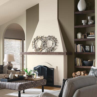 A living room with large fireplace, neutral colored walls, and bookshelf