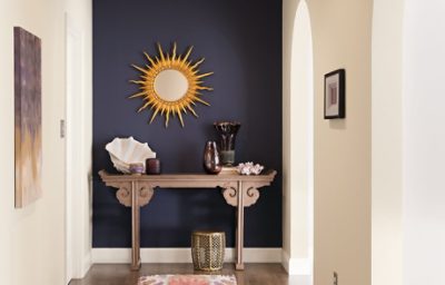 A purple accent entryway wall with a sun wall decoration and side table