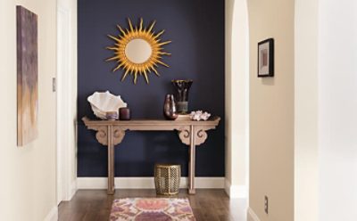 A purple accent entryway wall with a sun wall decoration and side table