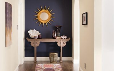 A purple accent entryway wall with a sun wall decoration and side table