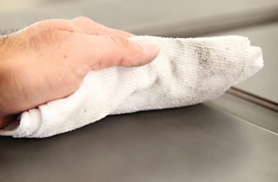 A person using a white cloth to wipe a surface.