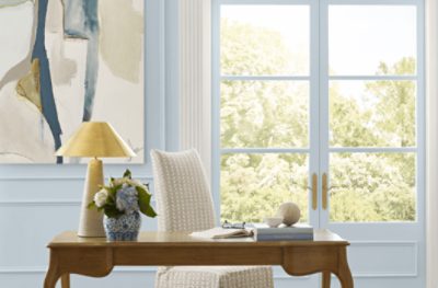 Office painted Sherwin-Williams Upward SW6239 with large window double doors and a beige chair paired with a wooden desk.