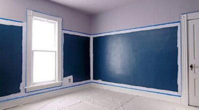 Using painters tape to paint the bottom of a wall.