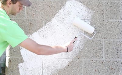A man using a roller to paint a garage white