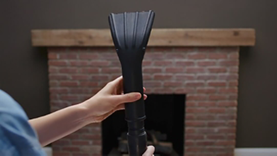 A woman holding a vacuum for a fireplace.