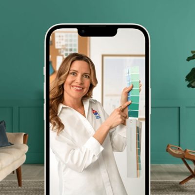 A phone showing a virtual color consultation with a woman holding up a fan deck.