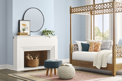 Bright living room painted in upward, with a fireplace, round mirror on the wall, area rug, and day bed.