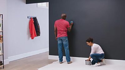 A couple is using sponges to clean dust and debris from a wall