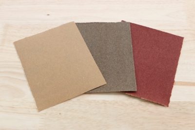 Three pieces of sandpaper with varying grit.