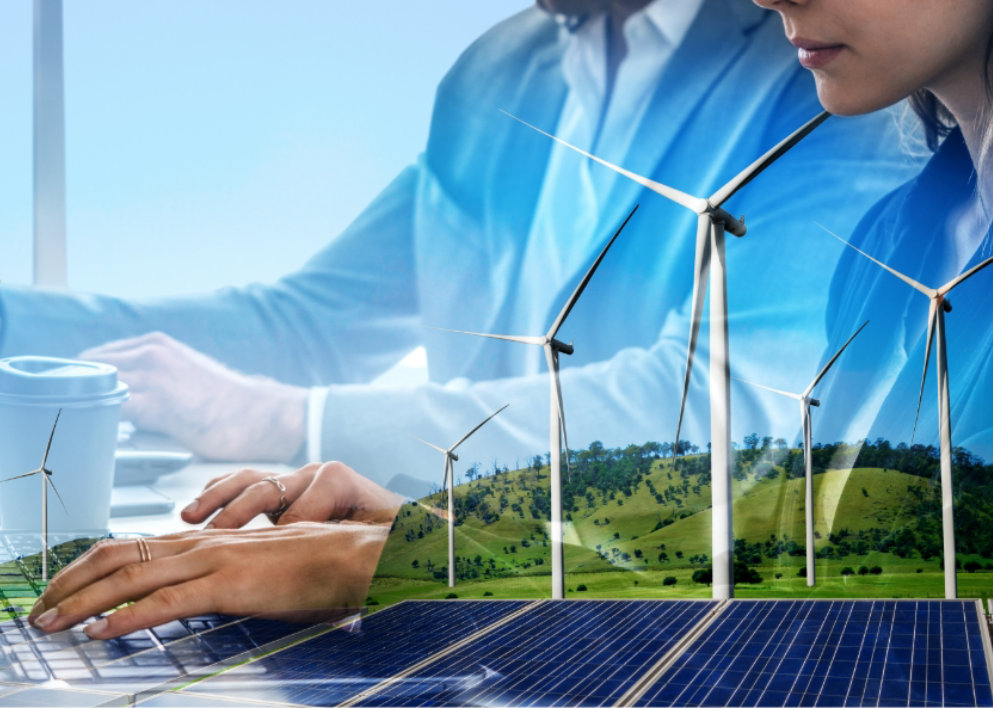 Wind turbines and solar panels in a field superimposed onto an image of two office workers at a computer