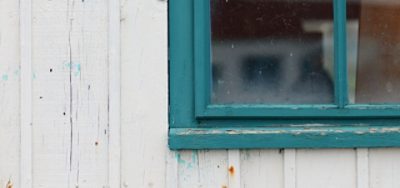 A close-up of a window frame with peeling paint.