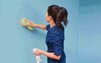 A woman washing a wall with a sponge.