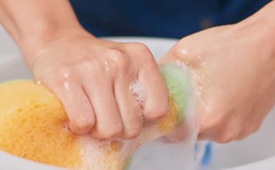 A man wringing a sponge with water from a bucket.