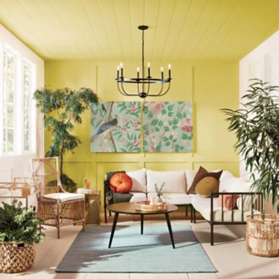 A sunroom with a yellow accent wall and ceiling.