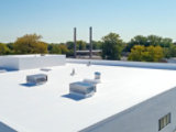 A white rooftop with HVAC or mechanical equipment, surrounded by a low parapet wall