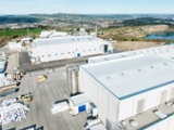 An industrial area with large white warehouse-style buildings and paved surfaces